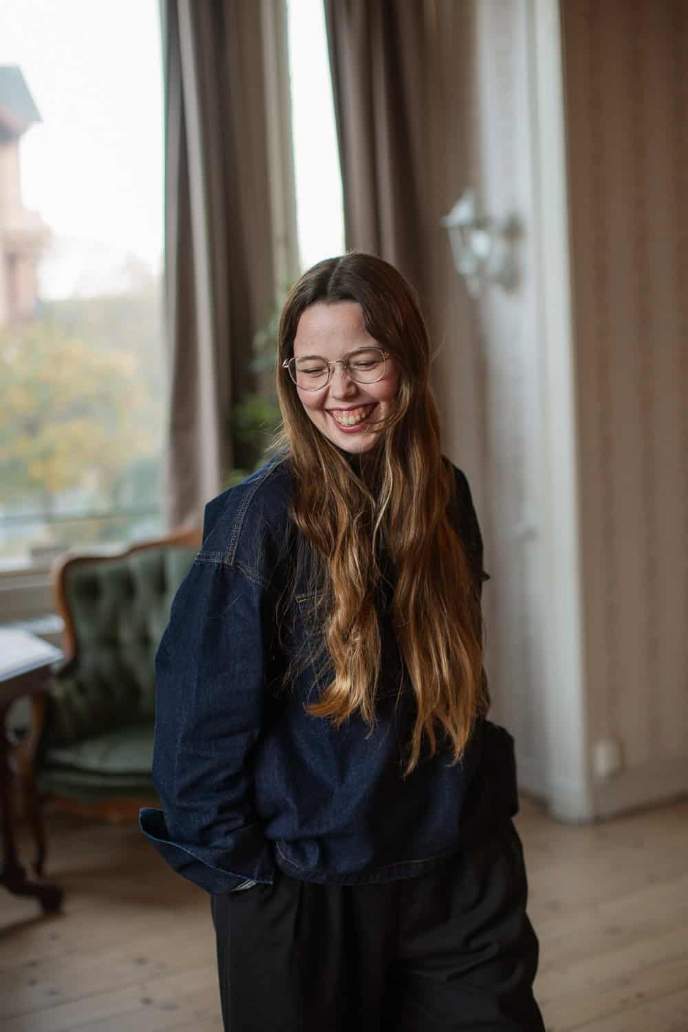 Hjemme i stua med smilende kvinne, innendørs, naturlig lys, koselig atmosfære.