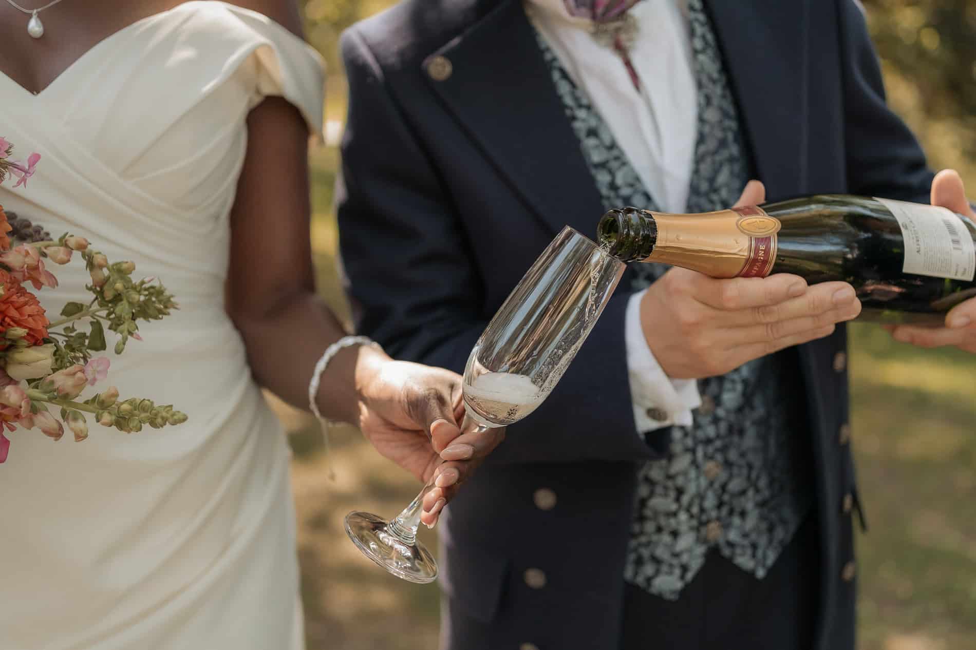 Bryllupspar skåler med champagne utendørs.