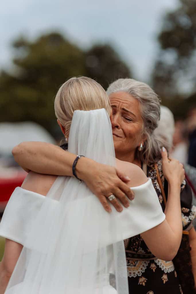 Bryllupsbilder av følelsesladet øyeblikk mellom brud og mor under vielsen.