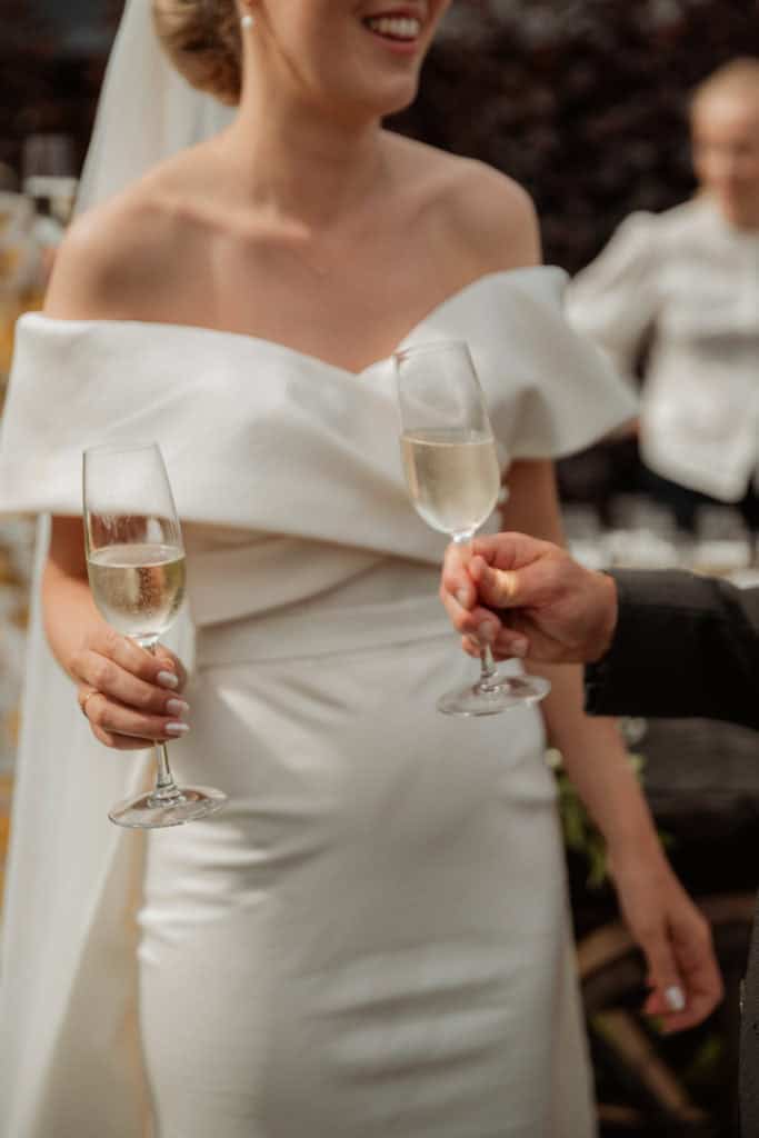 Kvinne i brudekjole holder champagneglass under bryllupet.