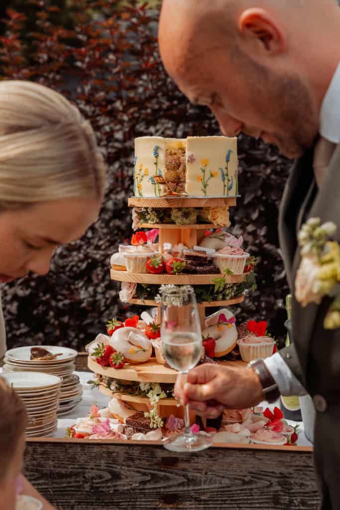 Bryllupskake med blomsterdekorasjon under bryllupet, omgitt av søte kaker og dessert.