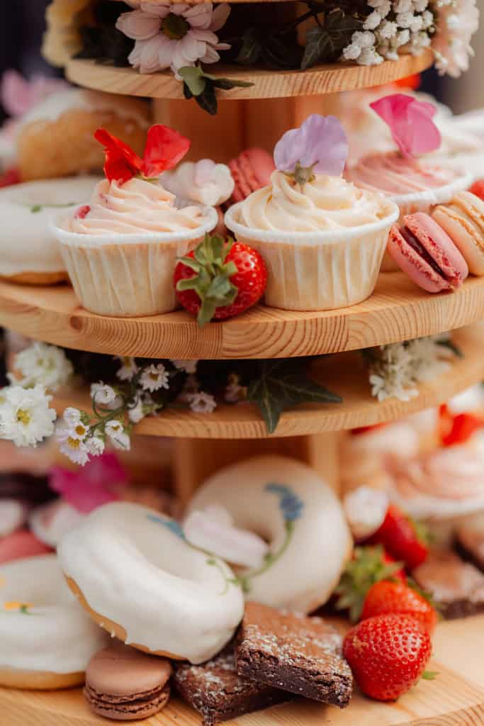 Nydelige cupcakes og søtsaker på bryllupsfest, dekorert med blomster og frukt.