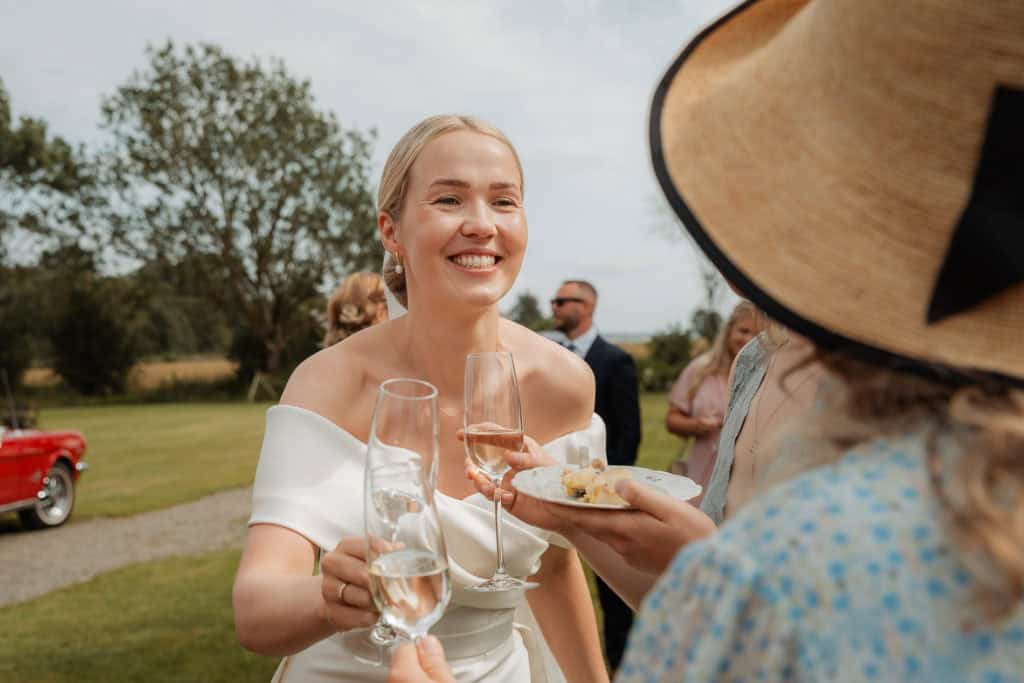 Bryllupsstemning med smilende brud og gjester under bryllupet, utendørs feiring med champagne og gle.