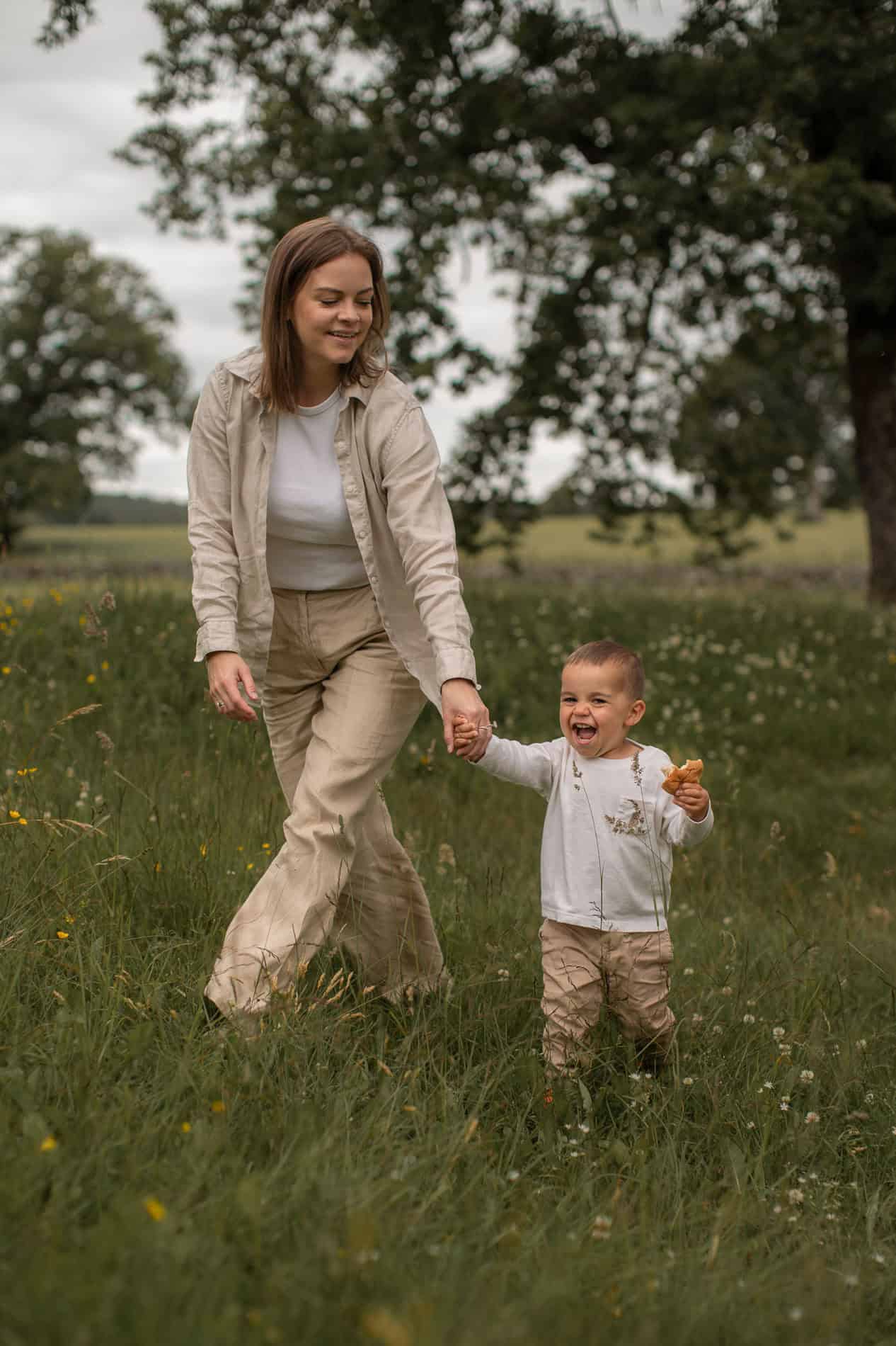 Familie går tur i grønt landskap med barn og mor, nyter utendørsaktiviteter.