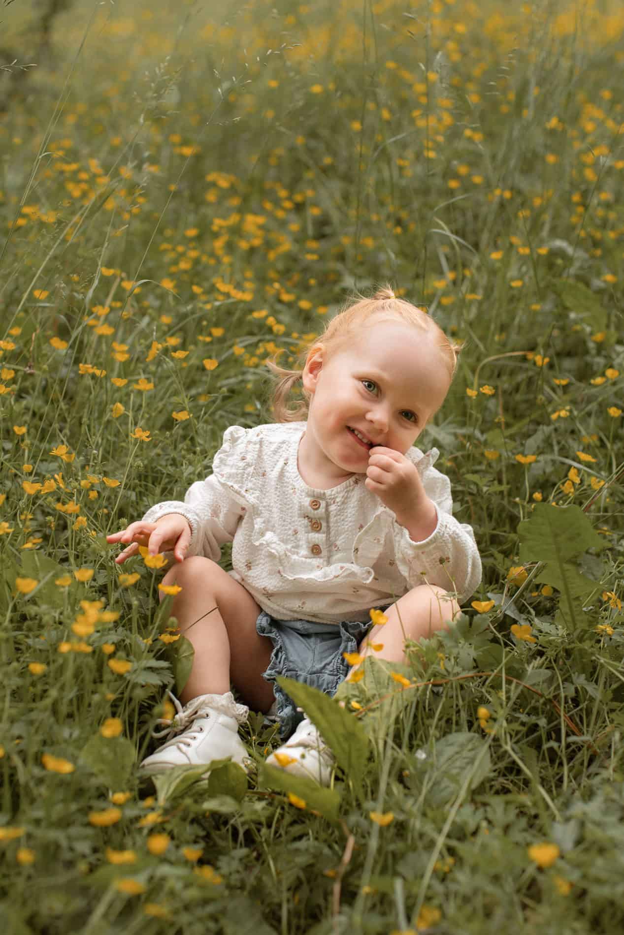 Barn i blomstereng med smilende ansikt.