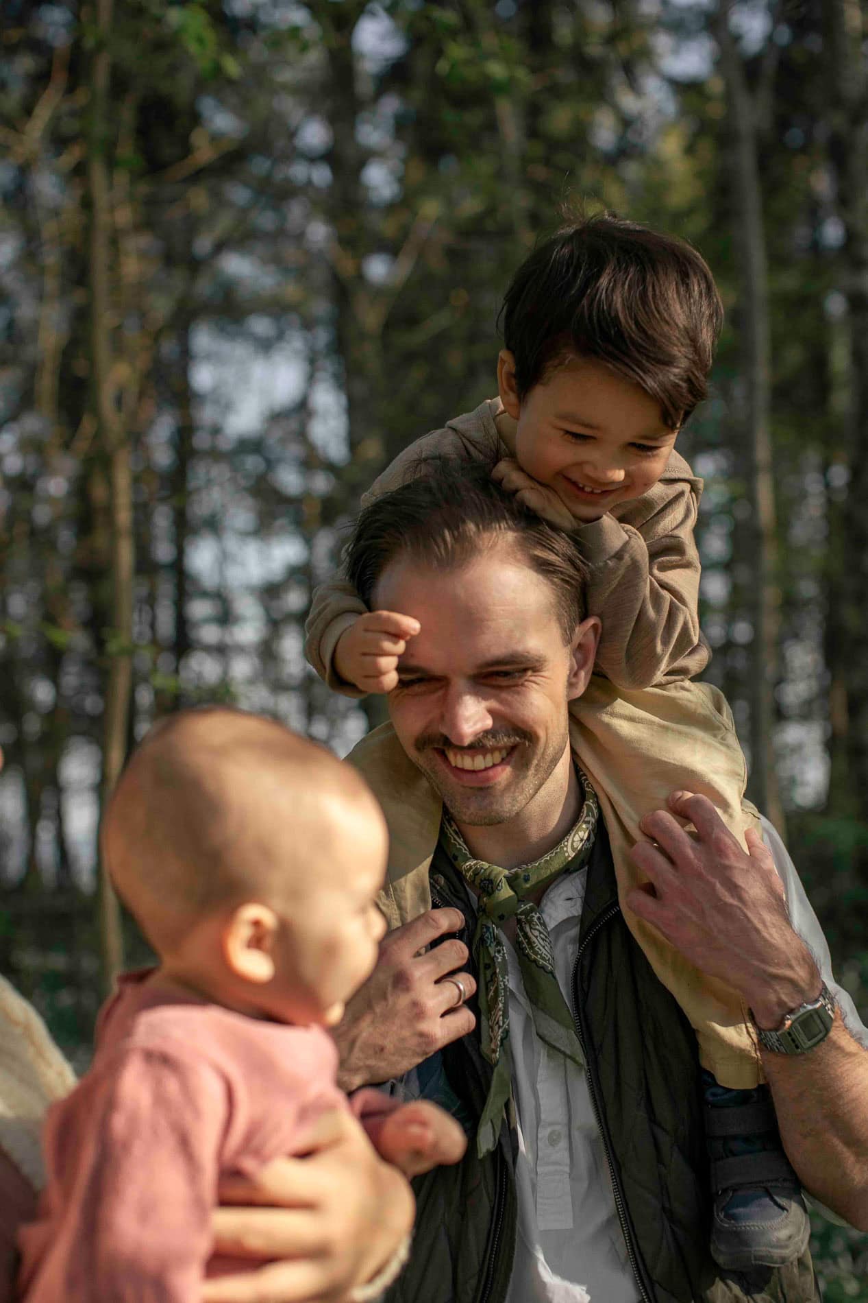 Familie med to barn i skogen, smilende og leende.