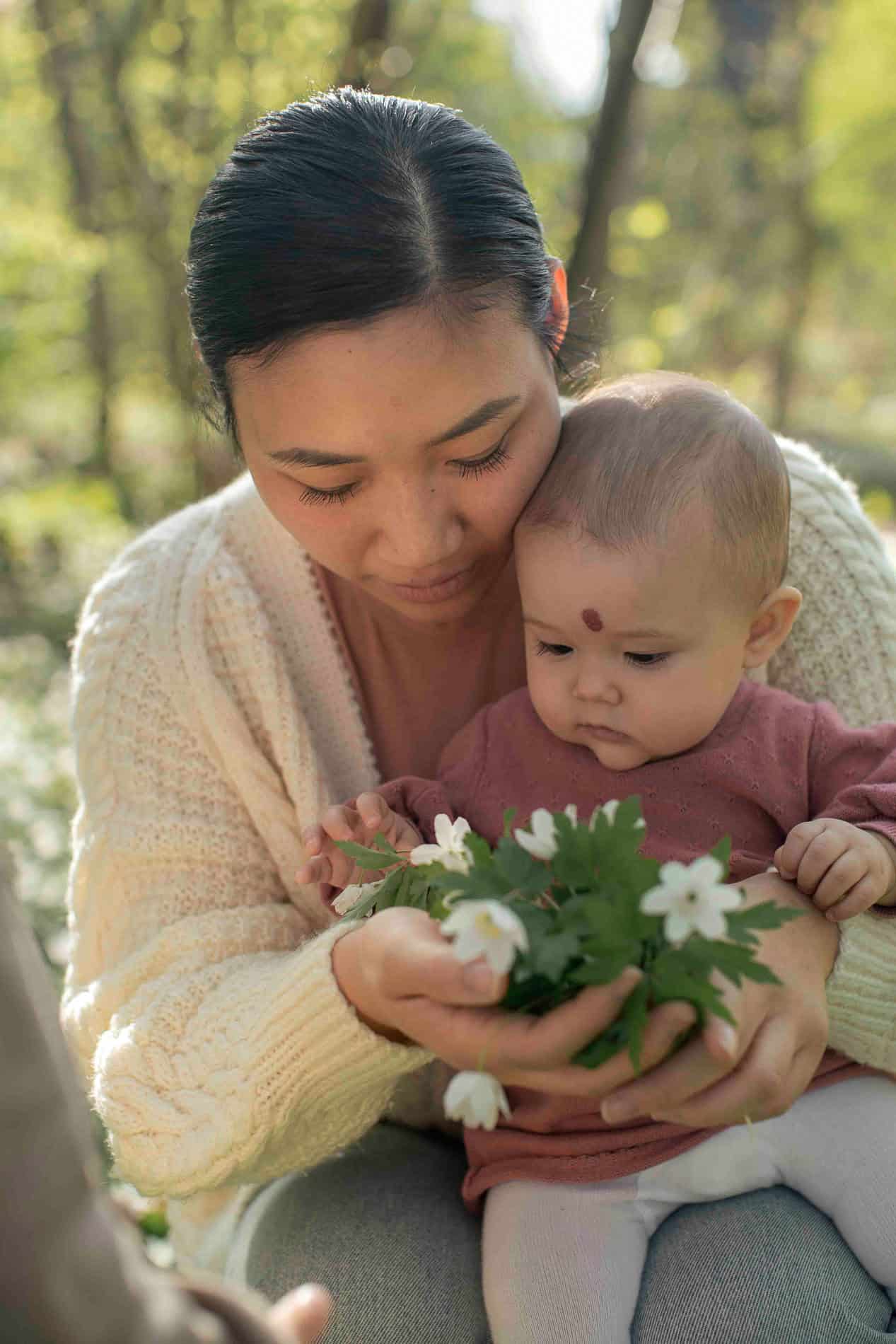 Mor og barn med blomster i utendørs miljø.