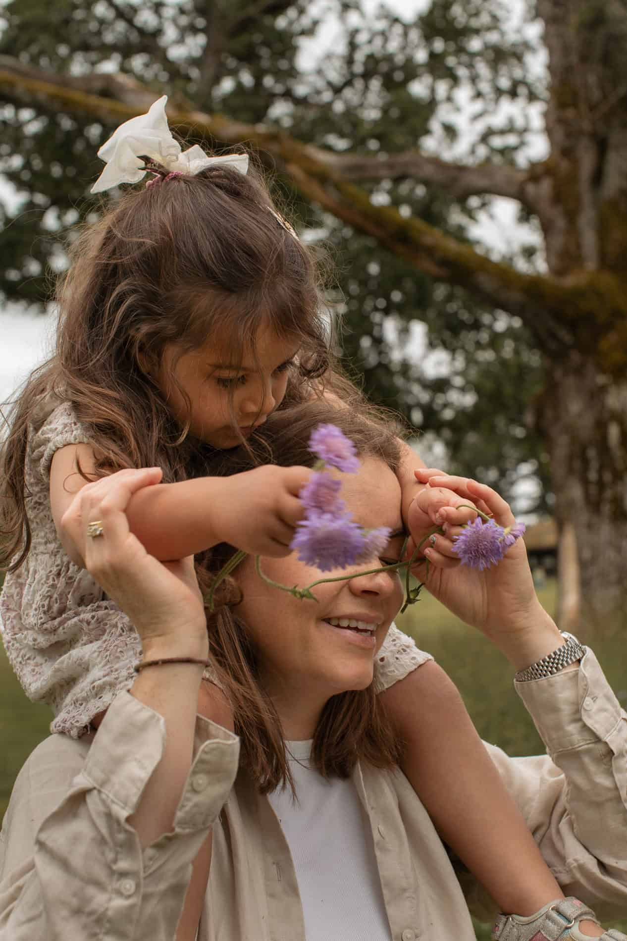 Barn og voksen med blomsterkrans i naturen, glede og samvær.