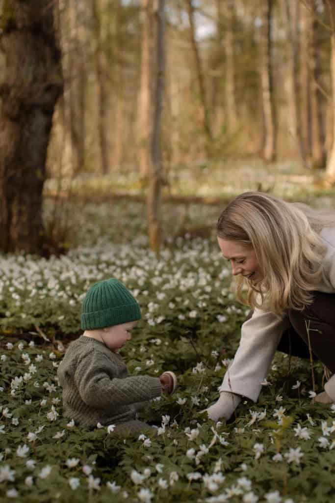 Barn og voksen plukker blomster i skogen.