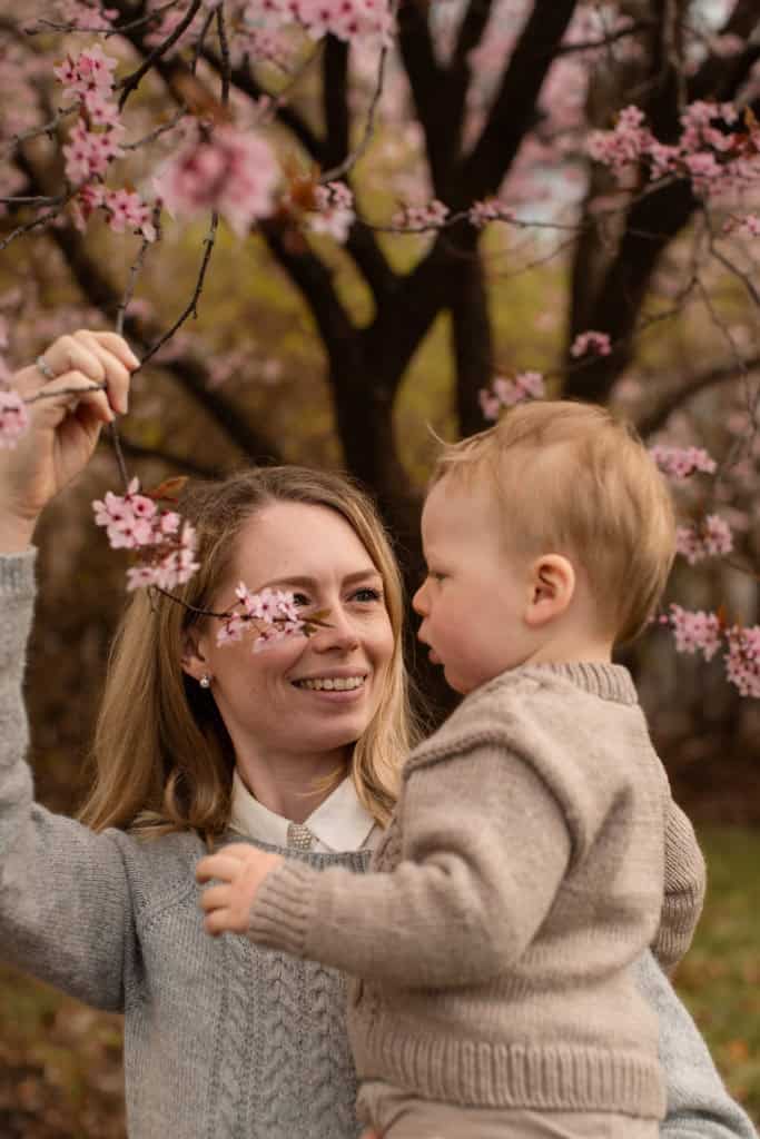 Nydelig bilde av en kvinne og barn under blomstrende trær med sesongens blomster.