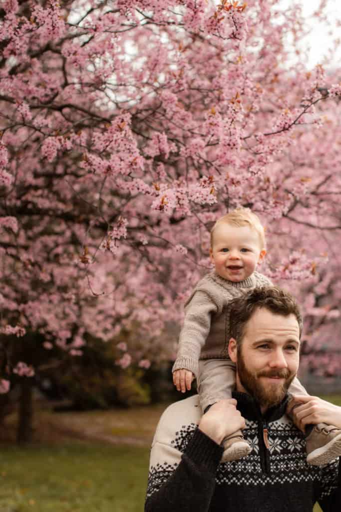 Familie med barn under blomstrende kirsebærtre i vårparken.