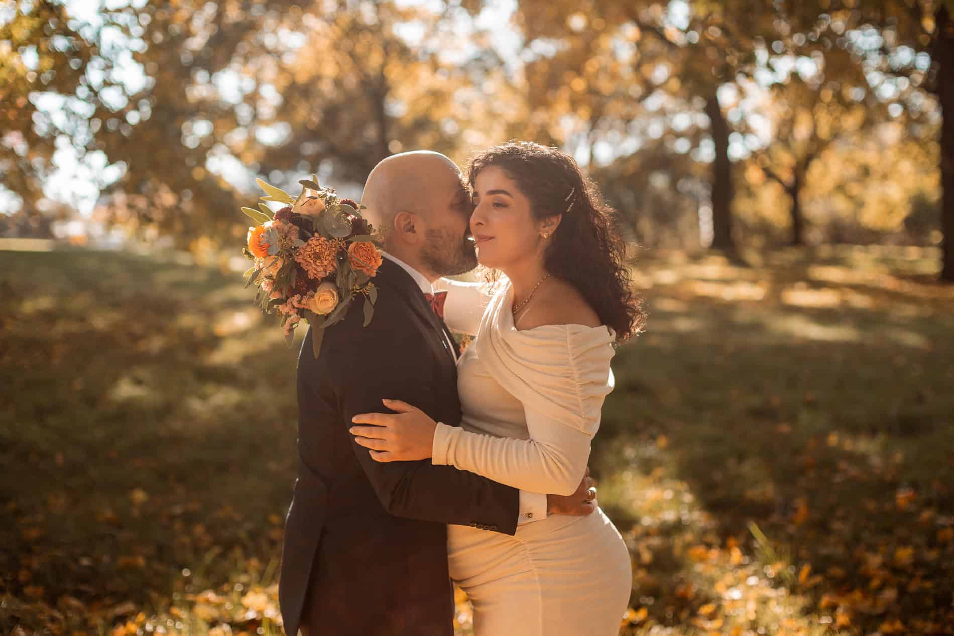 Bilde av et par som kysser under høsttrær, romantisk bryllupsfoto i Oslo.